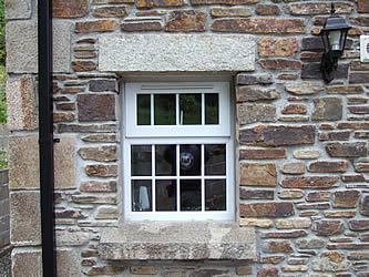 Close up of window with granite lintel and sill and corner quoins on the wall